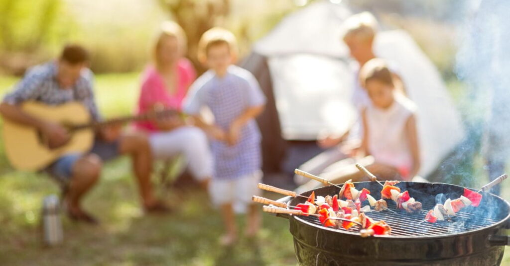 Perhe viettämässä kesäpäivää grillauksen äärellä.