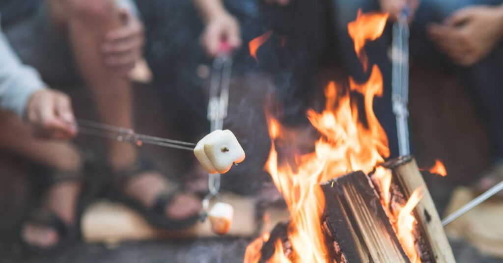 Ystäväporukka paistamassa vaahtokarkkeja nuotiolla.