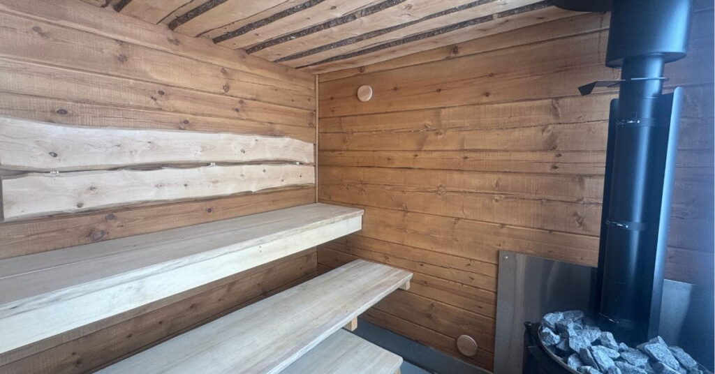Hirsisen ppihasaunan löylyhuone, jossa oikealla kiuas ja vasemmalla puiset lauteet
